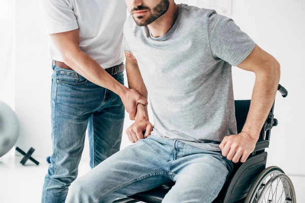 Physiotherapist helping handicapped man in Wheelchair during recovery — Stock Photo