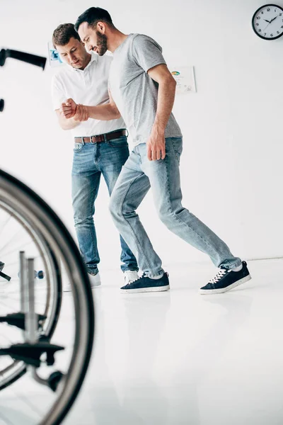 Fisioterapista che aiuta l'uomo handicappato a camminare durante la guarigione — Foto stock