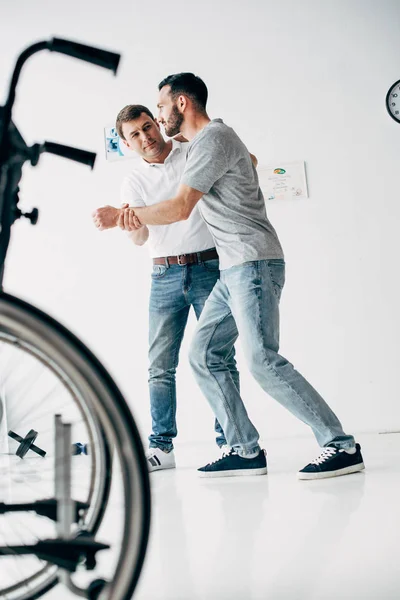 Physiotherapist helping handicapped man walking during recovery — Stock Photo
