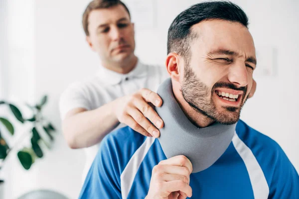Quiropráctico examinando jugador de fútbol en el cuello corsé en el hospital - foto de stock