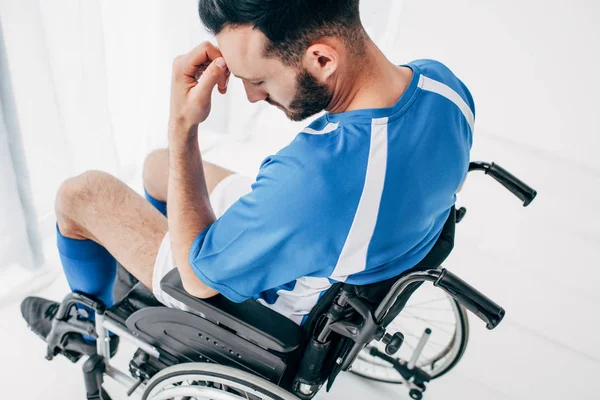 Chateado homem no futebol uniforme sentado em cadeira de rodas no hospital — Fotografia de Stock