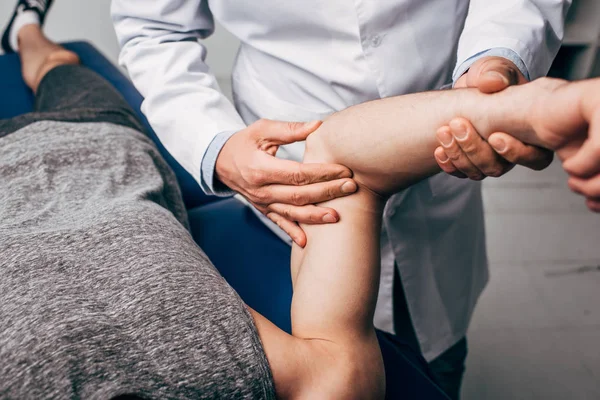 Vista recortada del brazo de masaje quiropráctico del paciente en el hospital - foto de stock