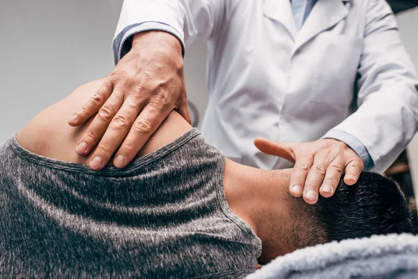 Chiropractor in white coat massaging neck of man — Stock Photo