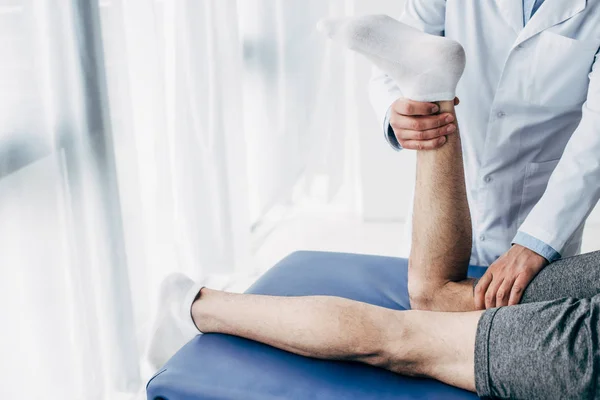 Cropped view of Physiotherapist stretching leg of patient in hospital — Stock Photo