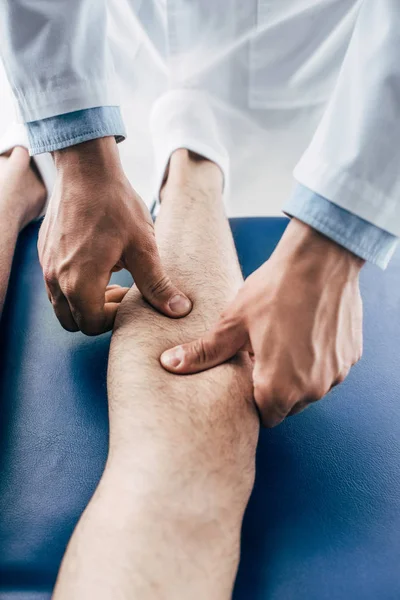 Vue partielle du masseur physiothérapeute jambe de l'homme à l'hôpital — Photo de stock