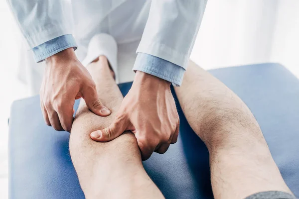 Visão cortada do fisioterapeuta massagem perna do homem no hospital — Fotografia de Stock