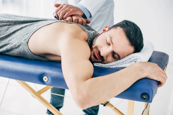 Chiropraktiker massiert Rücken eines auf Massagetisch liegenden Mannes im Krankenhaus — Stockfoto