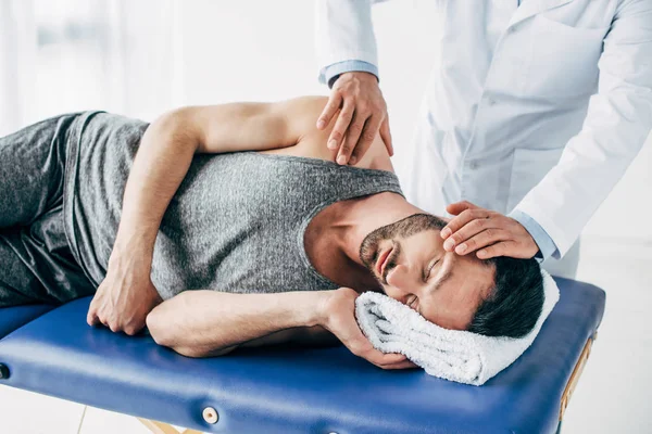 Chiropractor massaging neck of man lying on Massage Table — Stock Photo