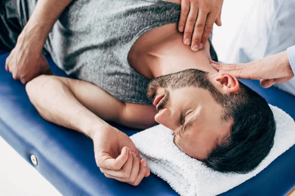 Chiropractor massaging neck of man lying on Massage Table — Stock Photo