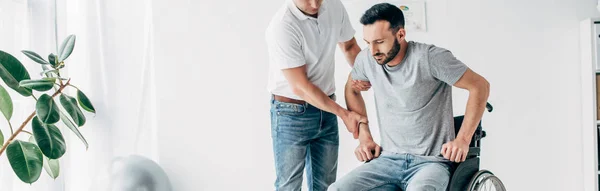 Tiro panorâmico de fisioterapeuta ajudando o homem deficiente durante a recuperação — Fotografia de Stock