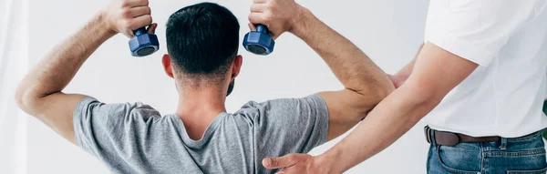 Panoramic shot of Physiotherapist helping patient with dumbbell during recovery — Stock Photo