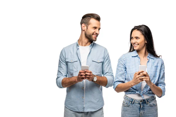Sonriente hombre y mujer joven utilizando teléfonos inteligentes aislados en blanco - foto de stock