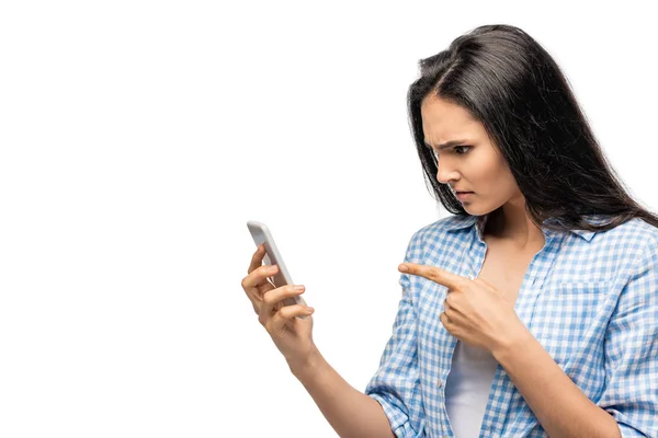 Menina confusa apontando com o dedo para smartphone isolado em branco — Fotografia de Stock