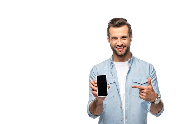 Sonriente hombre apuntando con el dedo al teléfono inteligente con pantalla en blanco aislado en blanco - foto de stock