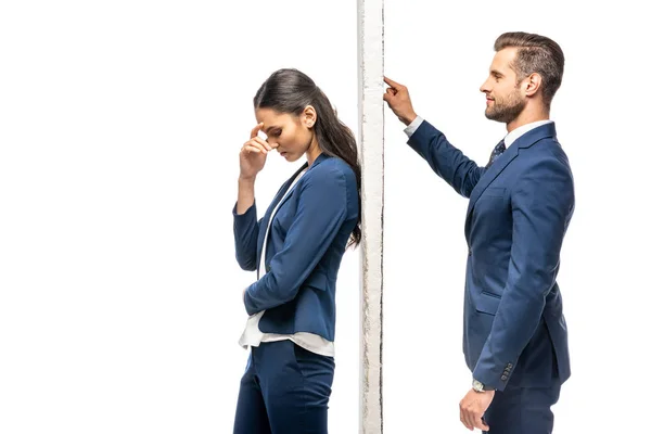 Homem de negócios bonito e bela empresária separada por parede isolada em branco — Fotografia de Stock