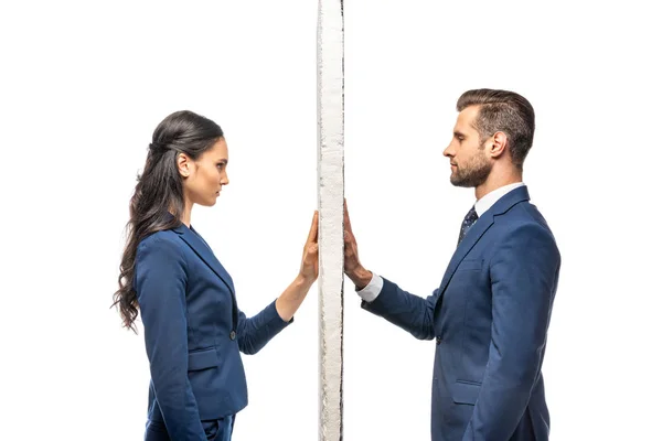 Hombre de negocios y mujer de negocios en trajes separados por la pared aislada en blanco - foto de stock