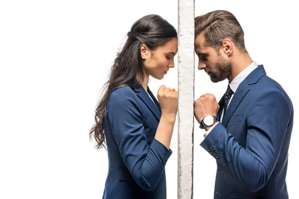 Triste hombre de negocios y mujer de negocios separados por la pared aislada en blanco - foto de stock