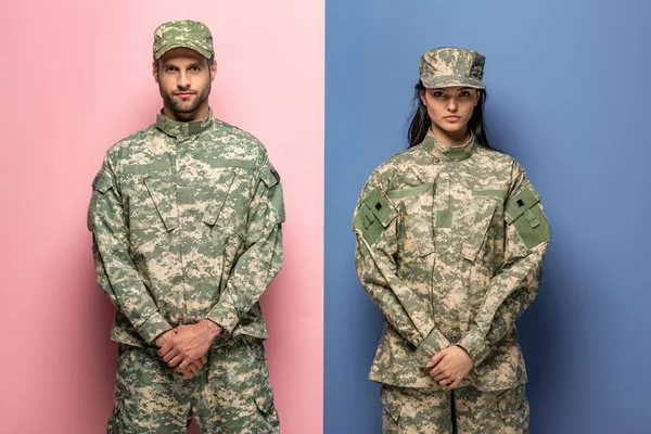 Man and woman in military uniform looking at camera on blue and pink — Stock Photo