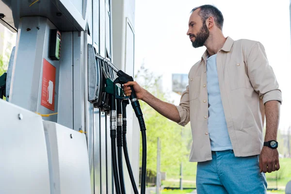 Vista a basso angolo dell'uomo che trattiene l'ugello del carburante alla stazione di servizio — Foto stock