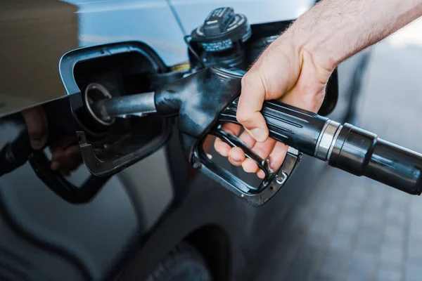Cropped view of man holding fuel pump and refueling car at gas station — Stock Photo