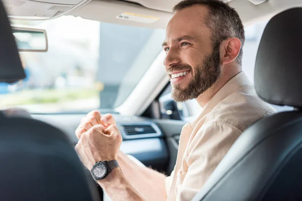 Uomo allegro gesticolare sorridendo e seduto in auto — Foto stock