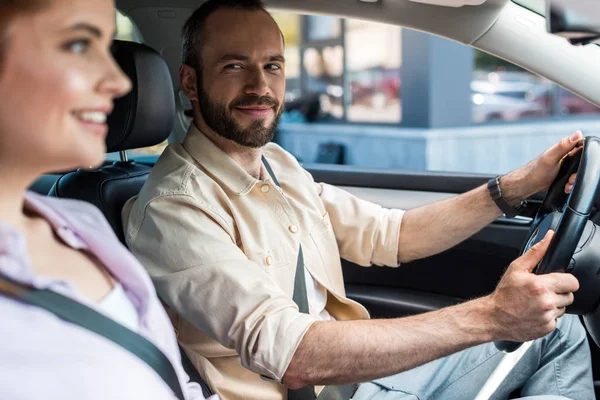 Selective focus of happy man driving car and looking at attractive woman — Stock Photo