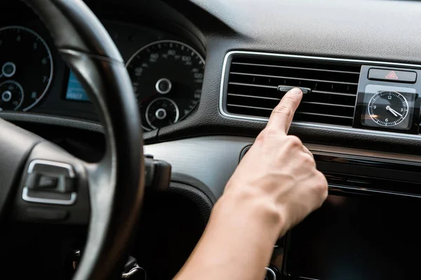 Vista cortada da mulher tocando interruptor de ar condicionado no carro — Fotografia de Stock
