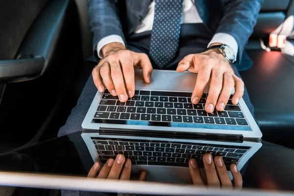 Selektiver Fokus von Geschäftsleuten, die auf Laptop im Auto tippen — Stockfoto