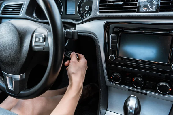 Abgeschnittene Ansicht einer Frau, die Autoschlüssel in Schlüsselloch steckt, während sie im Auto sitzt — Stockfoto