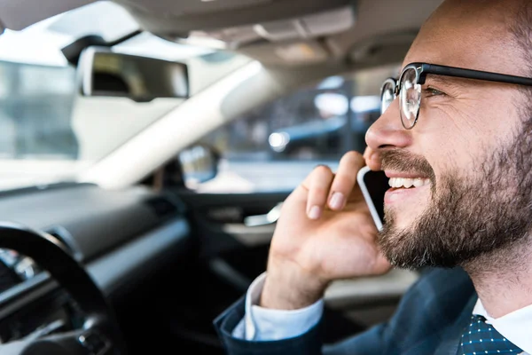 Gros plan de heureux homme d'affaires barbu parlant sur smartphone en voiture — Photo de stock