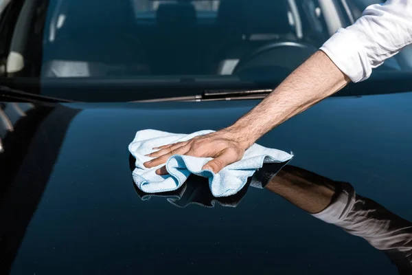 Vista cortada do homem limpando carro preto com pano branco — Fotografia de Stock