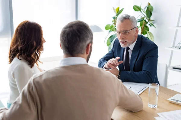 Selective focus of car dealer in glasses looking at customers in office — Stock Photo