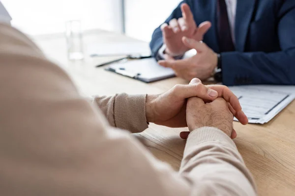 Ausgeschnittene Ansicht eines Mannes, der mit geballten Händen in der Nähe eines Autohändlers im Büro sitzt — Stockfoto