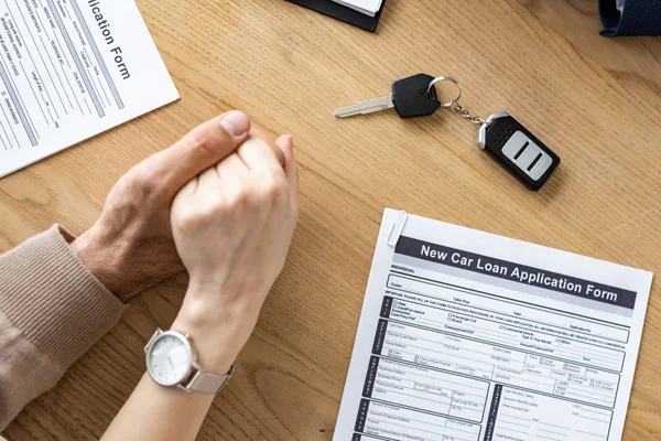 Ausgeschnittene Ansicht von Mann und Frau mit Händen in der Nähe von Autoschlüssel und Dokumenten — Stockfoto