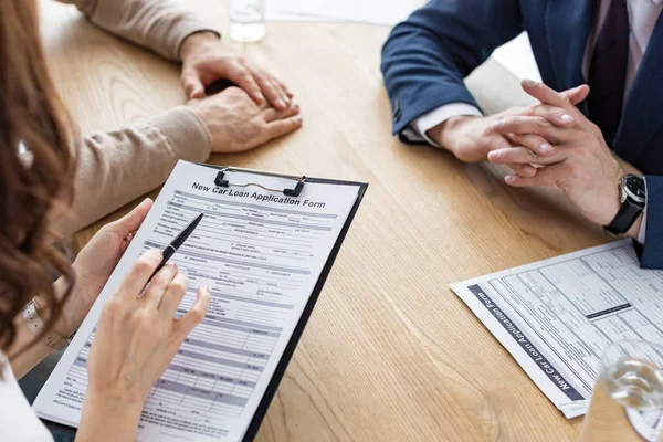 Cropped view of woman holding clipboard with contract and pen near men — Stock Photo