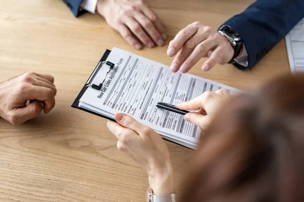 Overhead view of woman holding clipboard and pen near car dealer and man — Stock Photo