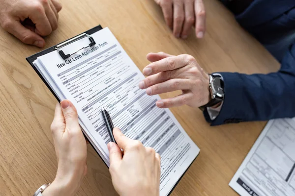 Ausgeschnittene Ansicht einer Frau mit Klemmbrett und Stift in der Nähe von Autohändler und Mann — Stockfoto