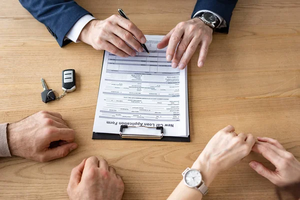 Vista ritagliata del documento di firma concessionario auto vicino ai clienti in ufficio — Foto stock