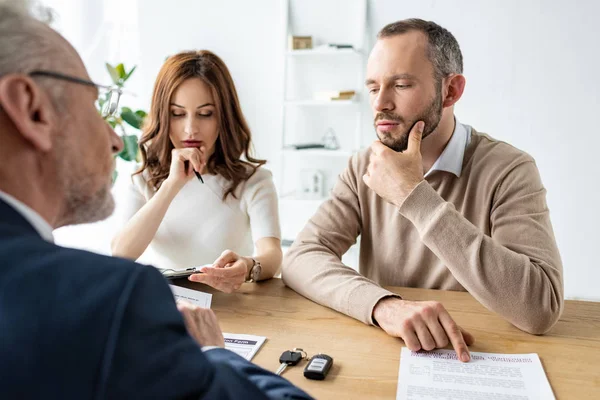 Foyer sélectif de l'homme et de la femme coûteux assis près du concessionnaire automobile dans le bureau — Photo de stock