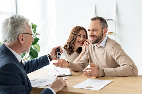 Selektiver Blick des gut gelaunten Mannes auf Autohändler mit Autoschlüssel — Stockfoto