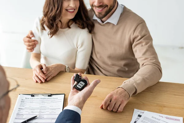 Blick auf Autohändler mit Autoschlüssel in der Nähe von Mann und Frau abgeschnitten — Stockfoto