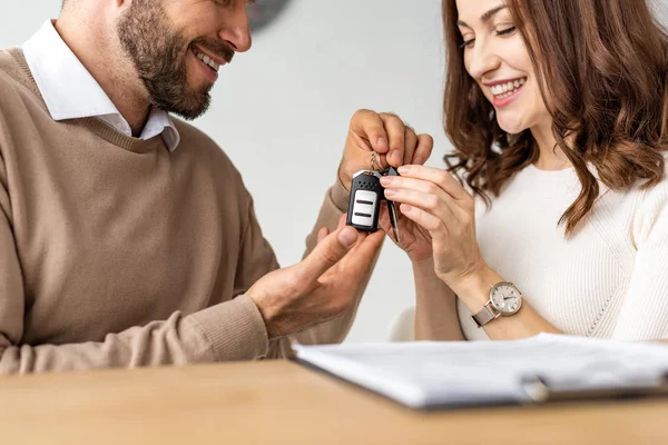 Selective focus of happy woman looking at car key in hands of bearded man — Stock Photo