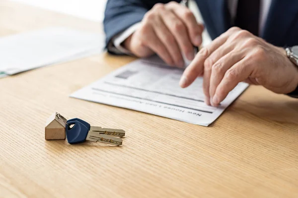 Foco seletivo do revendedor casa segurando caneta perto do contrato e chave do carro — Fotografia de Stock