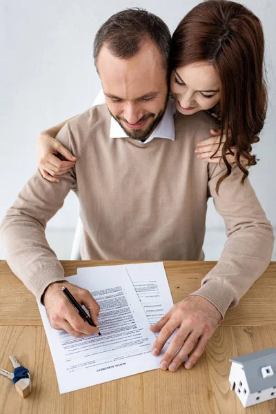 Happy man holding pen near document with rental agreement lettering and cheerful woman — Stock Photo