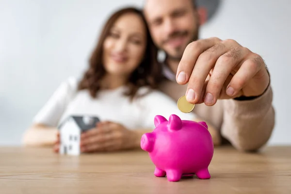 Mann steckt Münze in rosa Sparschwein und fröhliche Frau — Stockfoto