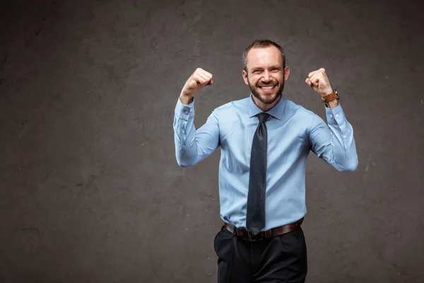Homem de negócios feliz em terno gestos enquanto comemorando em cinza — Fotografia de Stock