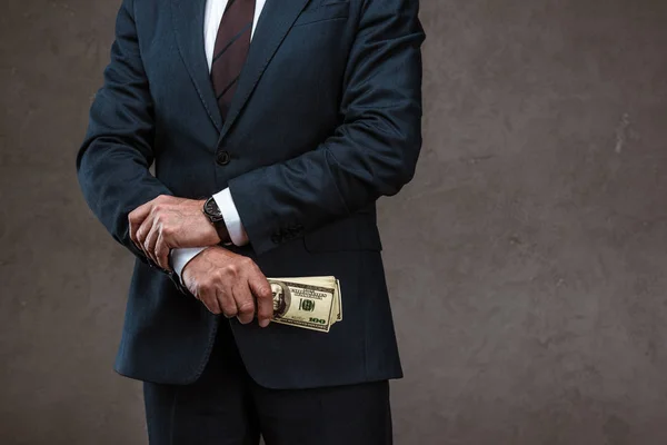 Vista ritagliata di uomo d'affari che detiene banconote in dollari in mano sul grigio — Foto stock