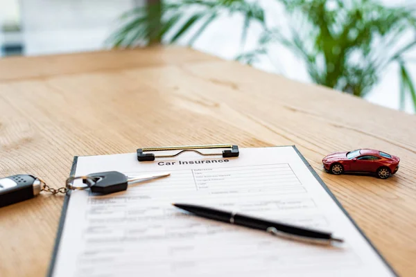 Foyer sélectif de la clé et du stylo de voiture sur le presse-papiers avec le document près de la voiture jouet — Photo de stock