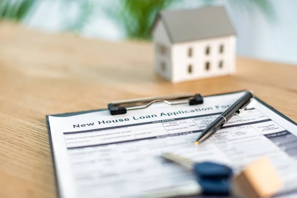 Selective focus of clipboard with document near keys and toy house — Stock Photo