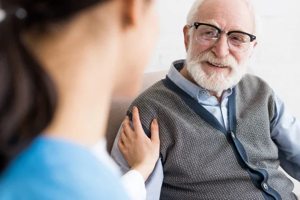 Selective focus of happy grey haired man looking at nurse — Stock Photo